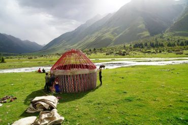group of tourists builidng a yurt in the mountains of kyrgyzstan, central asia