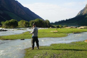 traveller trying to fish in the mountain river of kyrgyzstan
