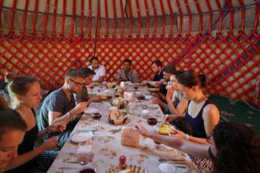 group of travellers eating local food in kyrgyzstan, central asia