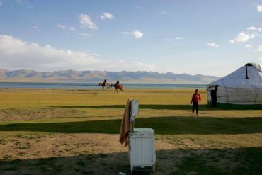 men riding horses near yurt at son kol in Kyrgyzstan & enjoying sunny weather