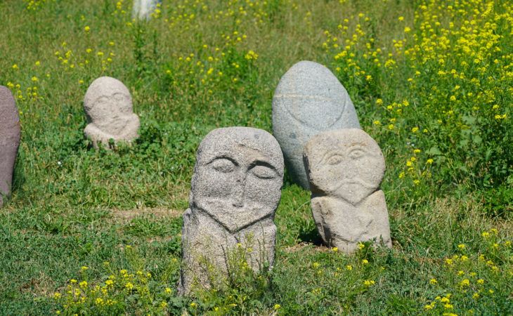 Balbals or anceint stone carvings on grass near burana in Kyrgyzstan trip